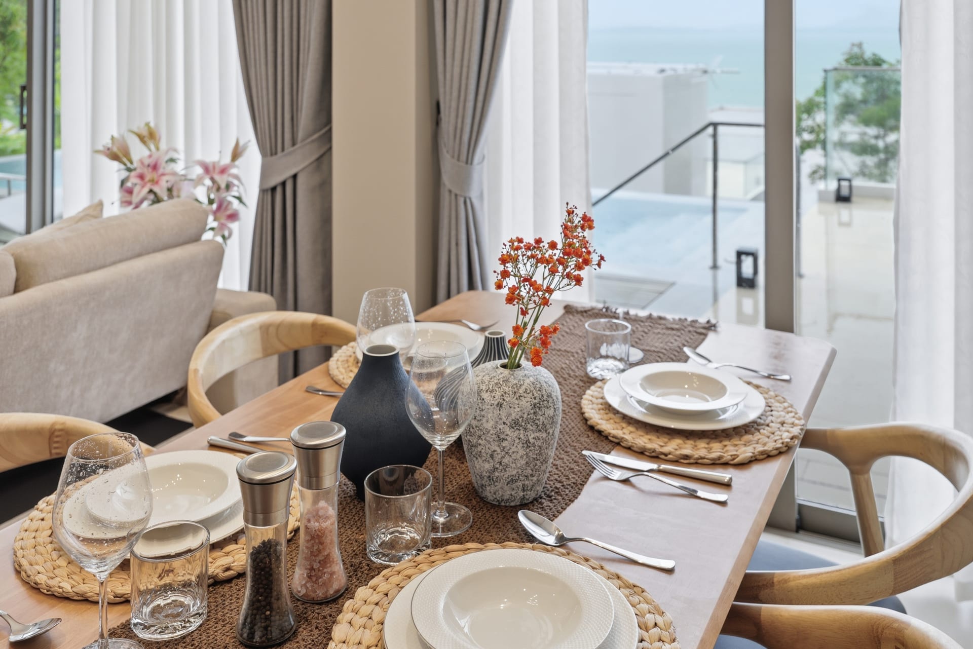 Dining table set for four with the Andaman Sea behind through floor-to-ceiling doors