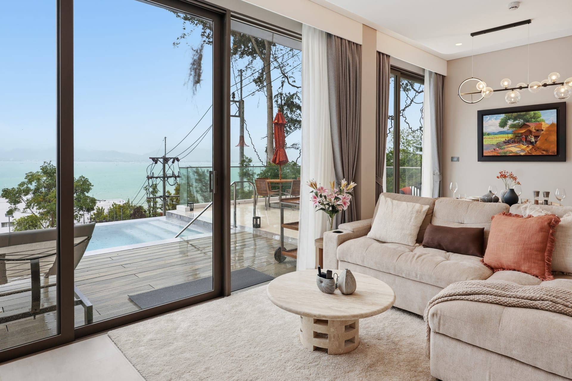 Open-plan great room with cloud-soft linen sofa and floor-to-ceiling sliding doors to the pool terrace