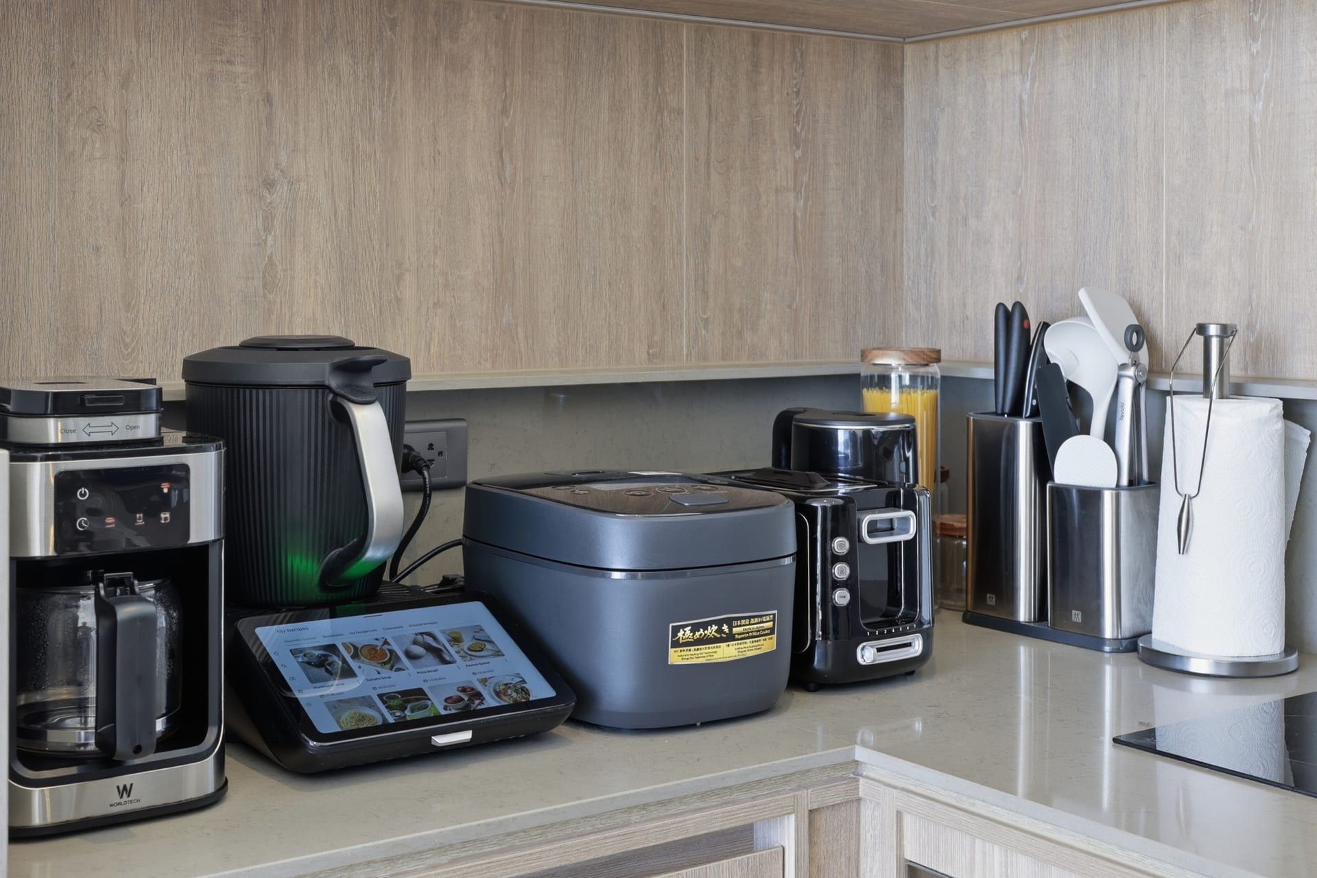 Counter detail of the kitchen's small appliances — coffee maker, kettle and rice cooker on the stone worktop