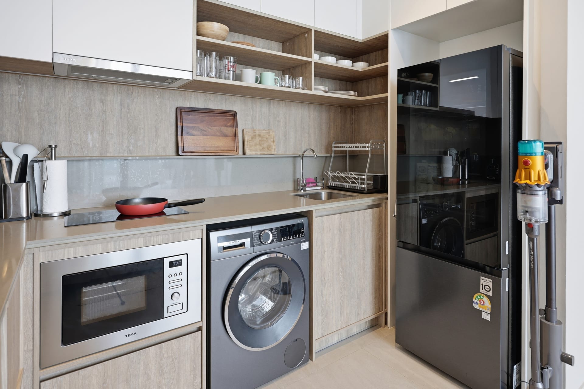 The fully equipped kitchen in daylight — washer/dryer, microwave, full-size fridge and stone counter