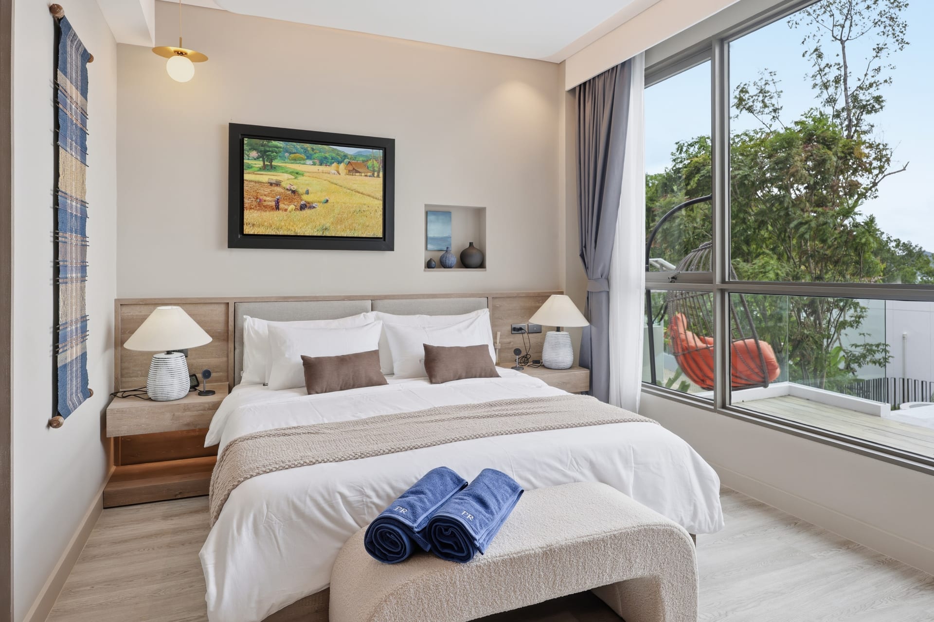 The second bedroom in bright daylight, bed dressed in white linen with tropical greenery at the window