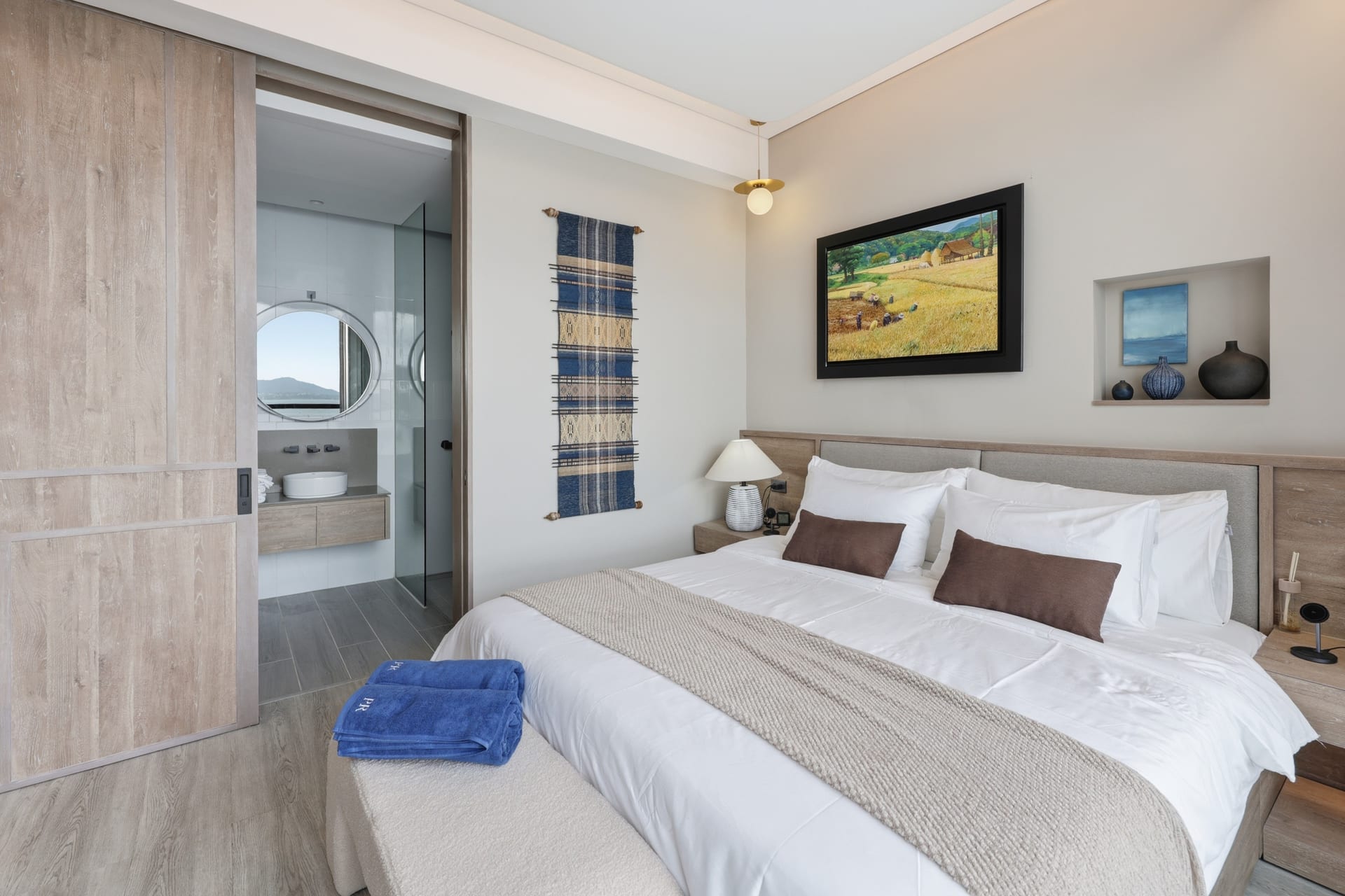 The second bedroom with a wall-mounted TV and marble feature wall, daylight from the window